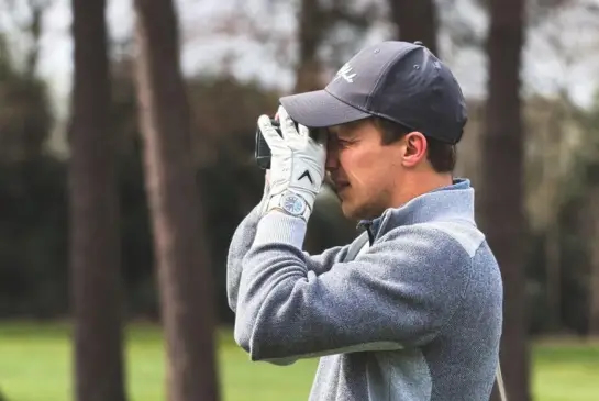 Alex Matthews using a laser rangefinder to check the distance to the pin at Whittington Heath Golf Club