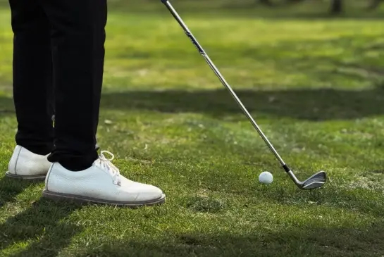 Alex Matthews at address with an iron, clubhead set behind the ball at Whittington Heath Golf Club